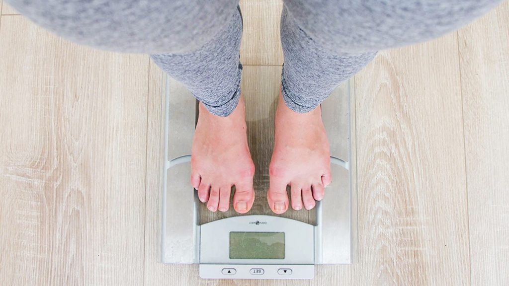 A woman weighing hereself on a weight scale