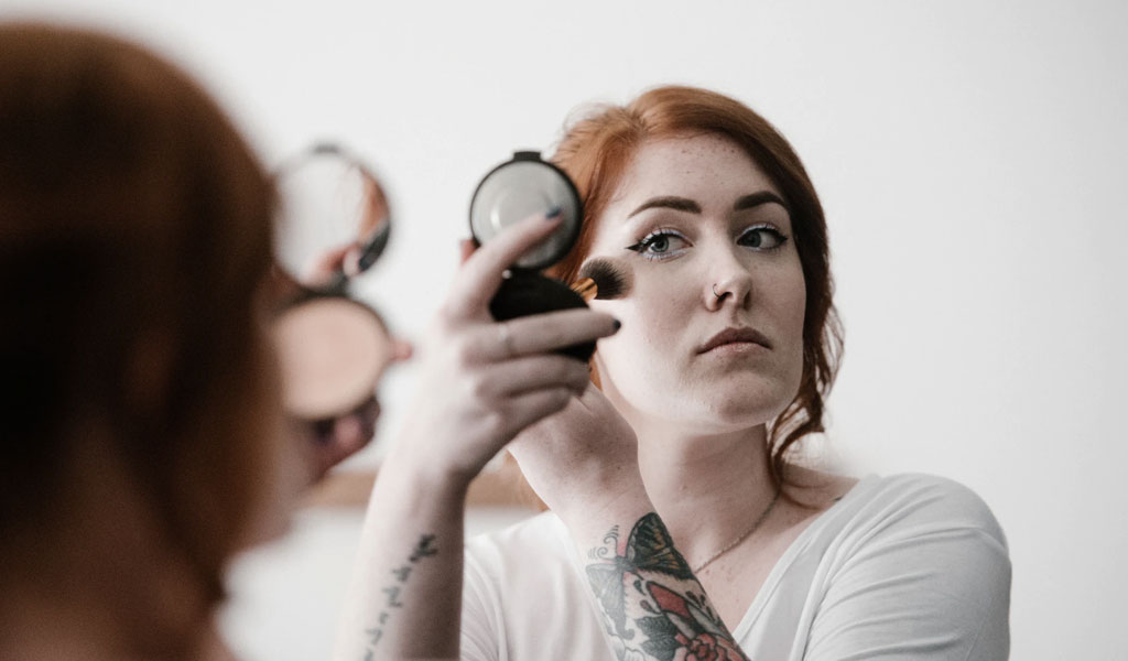 woman applying blush-on on her face