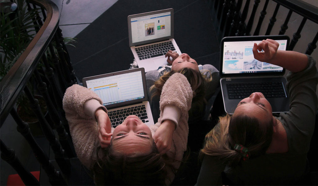 three person using laptops while sitting on ladder