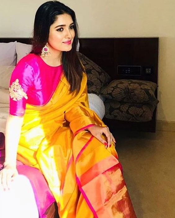 হলুদ শাড়ি পড়ে খাটে বসে একটি মেয়ে হাসছে