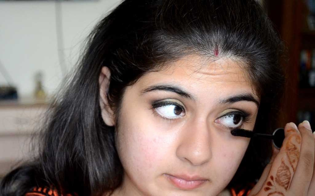 Indian woman applying Kajal on her eyes