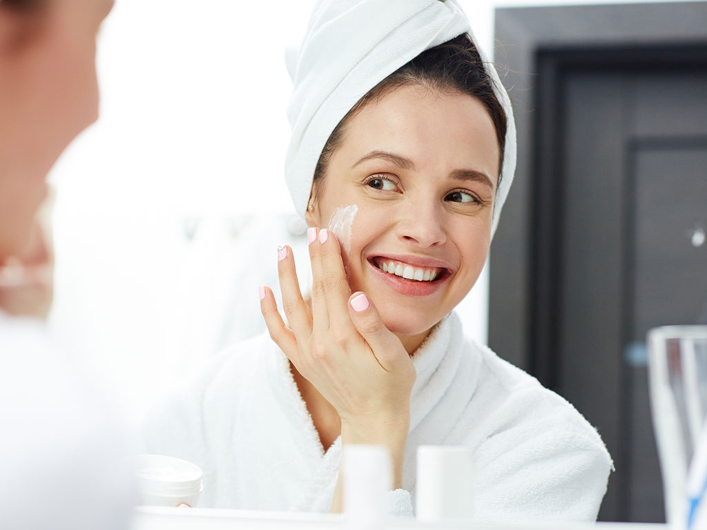 woman applying moisturizer to her face